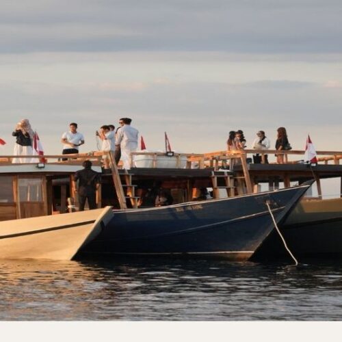 Sailing komodo 1 hari dengan tiga kapal wooden boat luxury bersandar saat sunset, tamu berdiri di dek atas